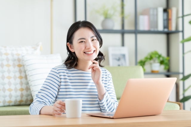 パソコンに向かってコップを持っている女性