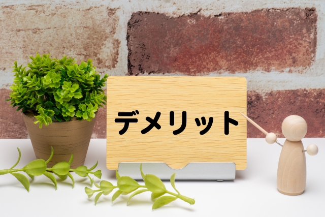 木目のメッセージボードにデメリットの文字とペグ人形
