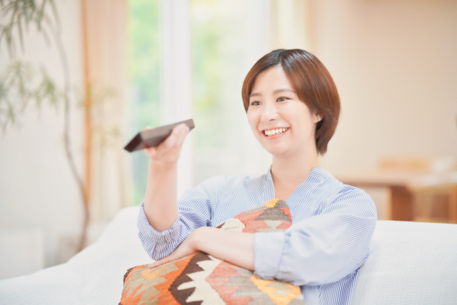 リモコンを手に微笑む女性