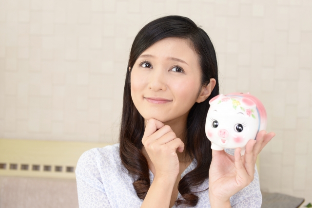 豚の貯金箱を持って妄想している女性