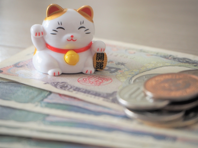 紙幣の上に招き猫とコインがのっている