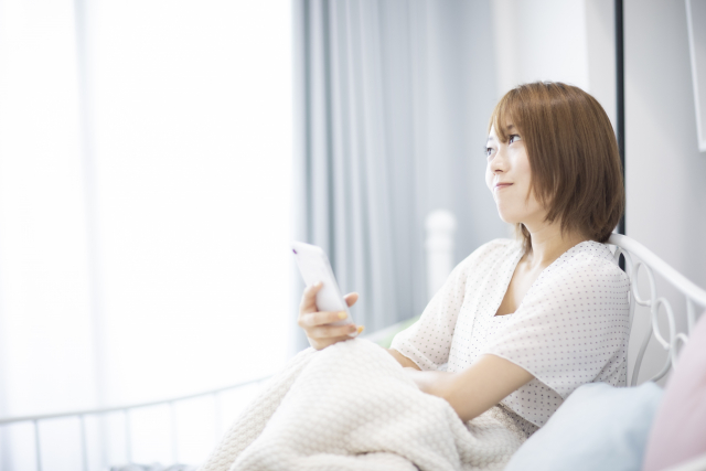 スマートフォンを片手に悩み女性