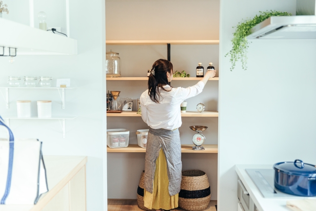 棚にものを片づける女性の後ろ姿