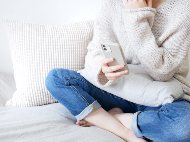 スマートフォンを見ながら悩む女性