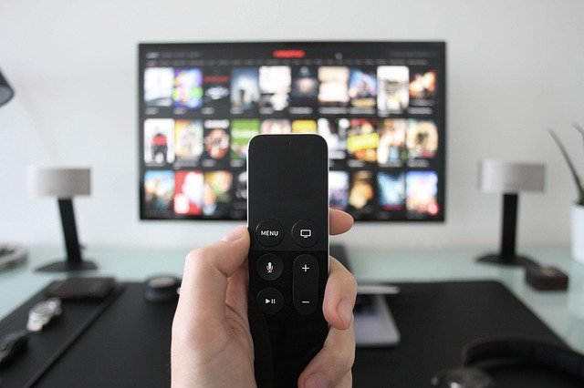 テレビのリモコンを持ち、どのチャンネルにしようか悩んでいる人