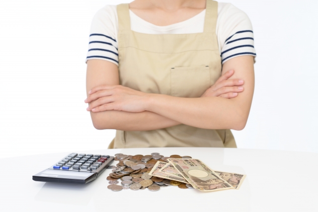 電卓とお金の前で腕組みをする女性