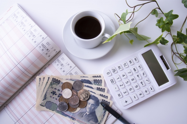 珈琲を飲みながら家計簿とお金と電卓を使っている