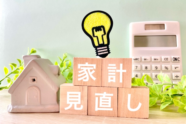 家計簿見直しと書かれているブロックと家と電卓の模型